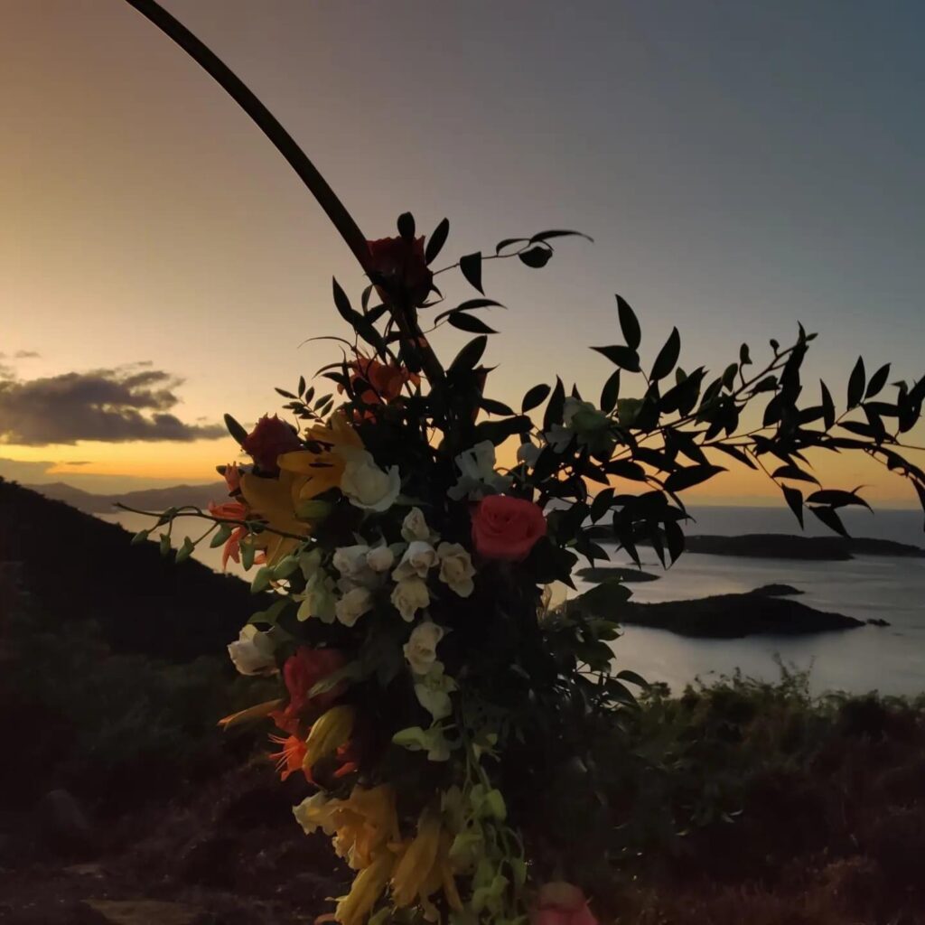 Flower-covered wedding arch at sunset over the bays