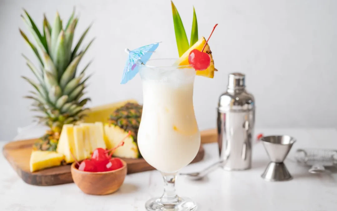 Pina colada recipe served in a hurricane glass with pineapple, cherry and coconut