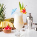 Pina colada recipe served in a hurricane glass with pineapple, cherry and coconut