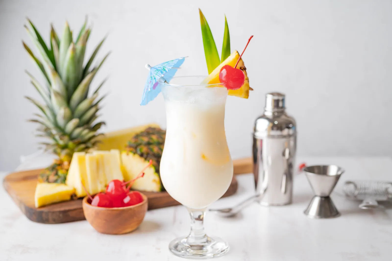 Pina colada recipe served in a hurricane glass with pineapple, cherry and coconut