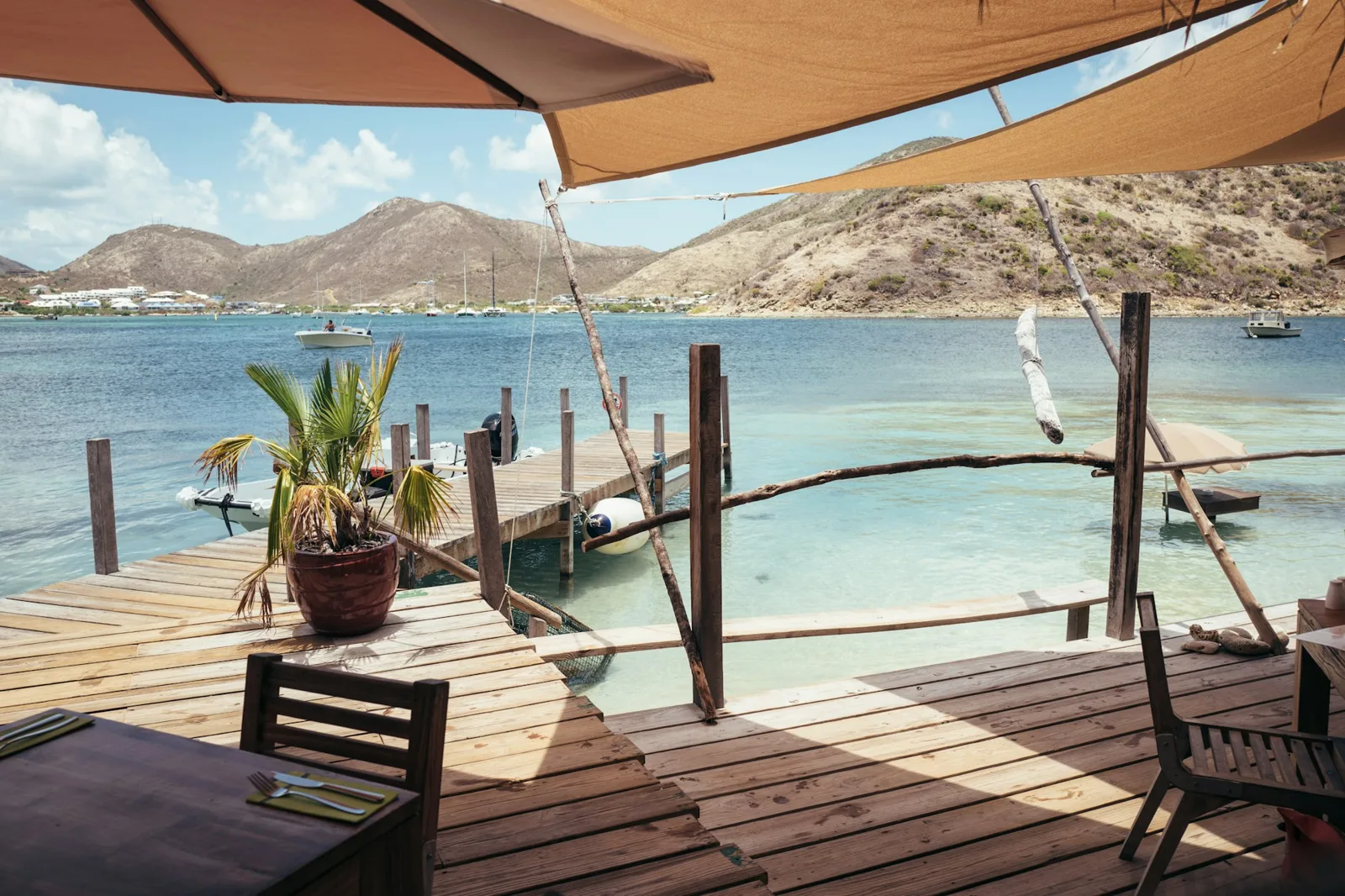 Open-air waterfront deck with tables overlooking a turquoise Caribbean bay on a sunny day