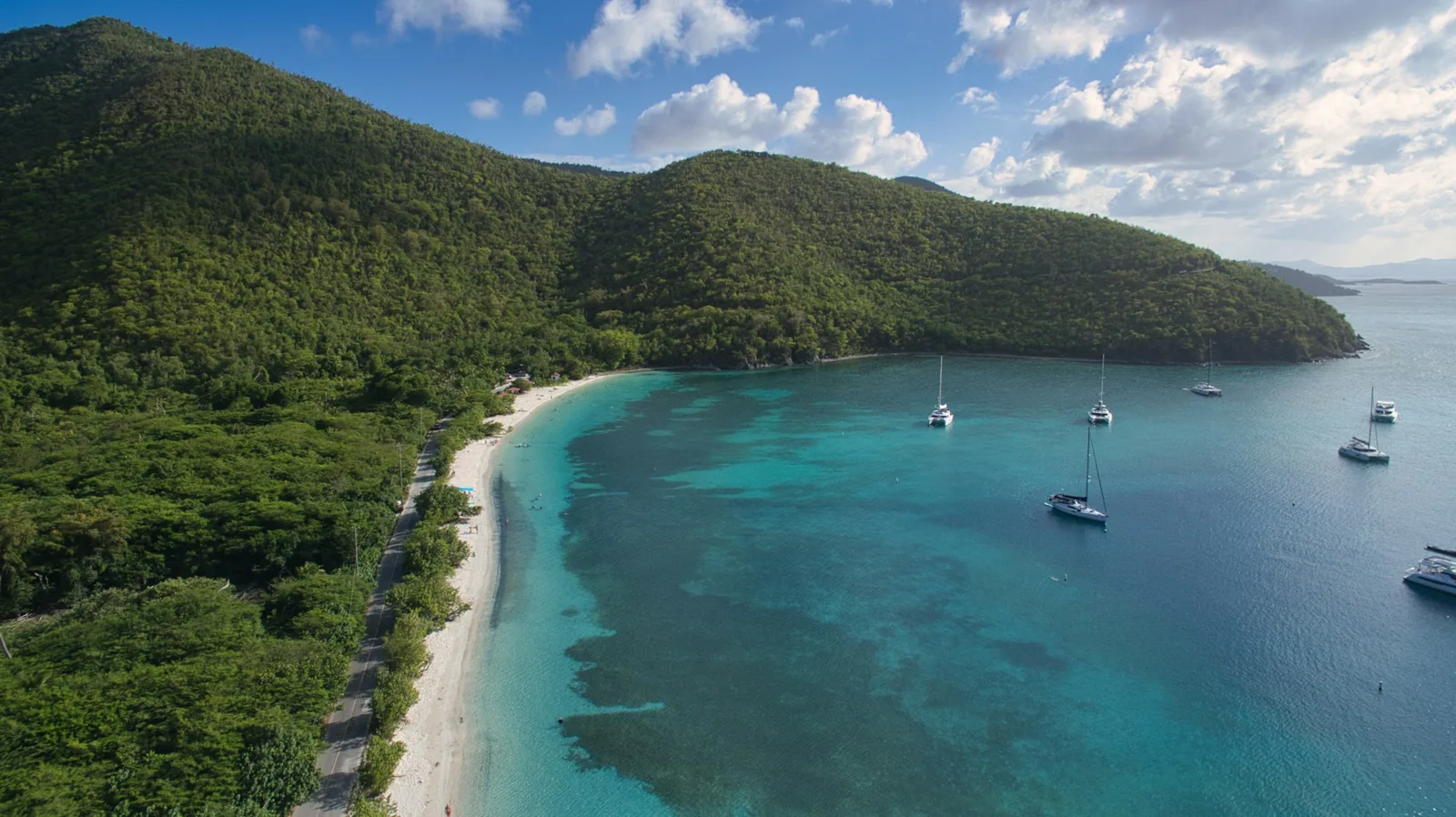 Green hills and a turquoise bay with sailboats on St. John, near St John restaurants on the north shore